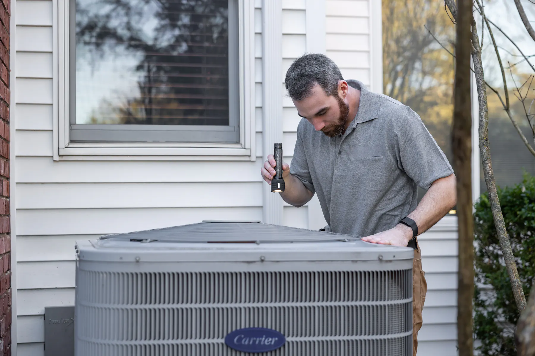Can Heating Cooling technician inspecting an outdoor air conditioning unit